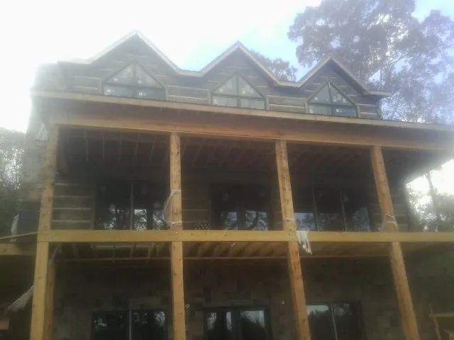 Dormers and porch framing on a large log home under construction — Roof Coating work by our crew in Elbing