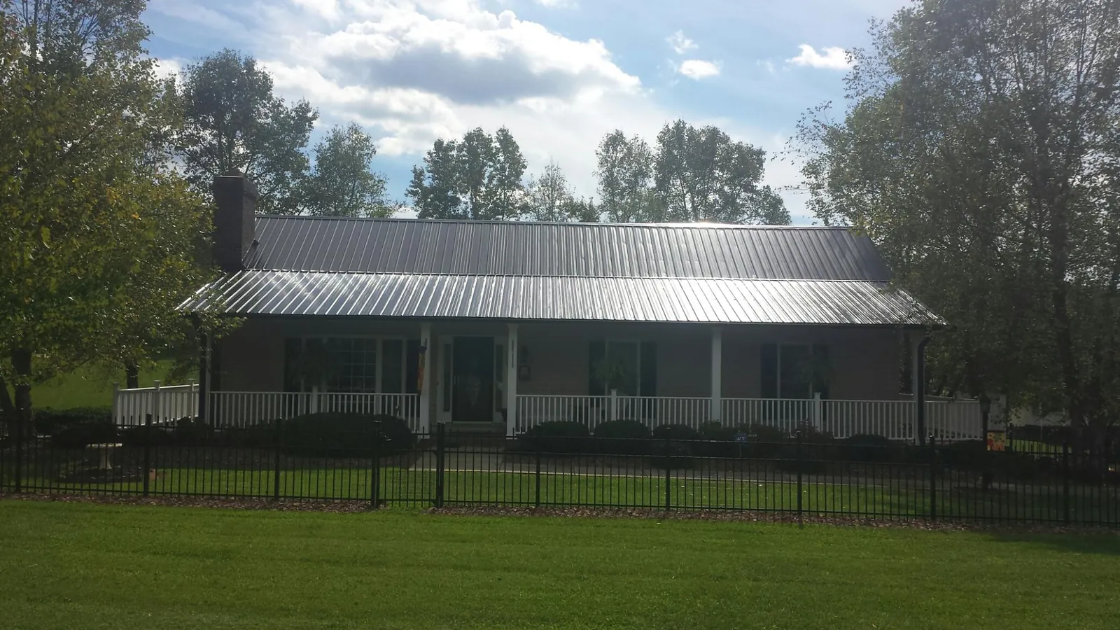 Gray metal roof on a brick ranch with a full width front porch — Gutter Guard Installation work by our crew in Elbing