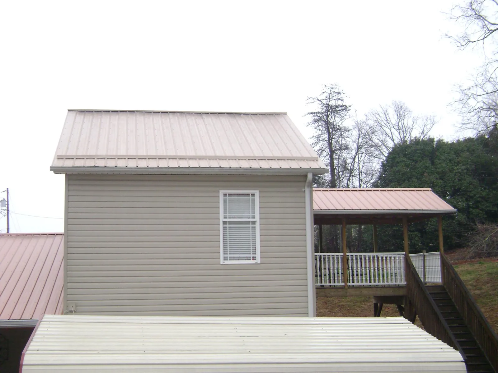 Tan metal roofs on a two story addition and attached porch, from a Roof Replacement job in Elbing